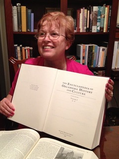 Linda D. Wilson holds one volume of "The Encyclopedia of Oklahoma History and Culture"