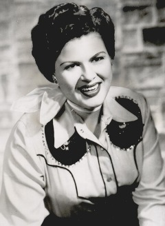 Entertainer Pasty Cline wearing Western wear and a scarf, smiles at the camera.