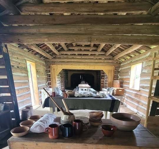 Tables in the Fort Gibson Stockade mess hall displaying kitchen equipment, stoneware bowls and wooden utensils