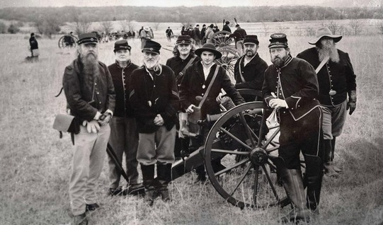 Aged photo shows current day members of the 1st Arkansas Mountain Artillery pose in Union uniforms around a Mountain Howitzer cannon.