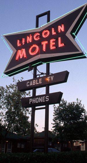 Lincoln Motel Neon sign is lit at twilight, rising above a series of cottages at the motel.
