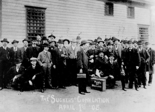 A group of men gathered for a photo outside the Enid Jailhouse April 1, 1905. They are wearing suits, ties, and hats.