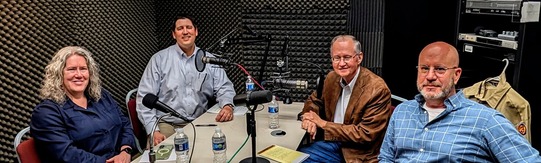 Lynda Ozan, Trait Thompson, Dr. Bob Blackburn, and Michael Mayes seated at a table with microphones in the podcast recording room. 