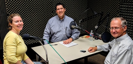 Elizabeth Anthony, Trait Thompson, and Dr. Bob Blackburn seated in a podcast recording studio in front of microphones.