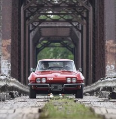 A red sportscar drives across a driveable section of Route 66 in Claremore