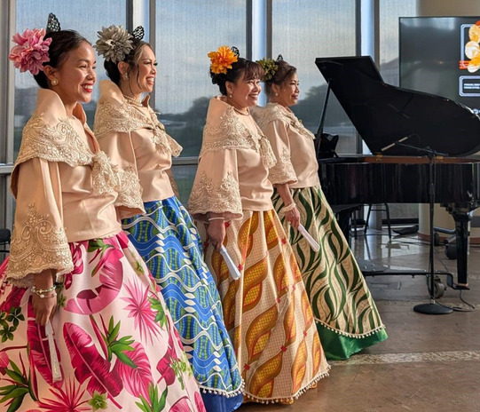 Women with beautifully patterned traditional Asian clothing with intricately embroidered tops and shawls stand together in a group of 4.