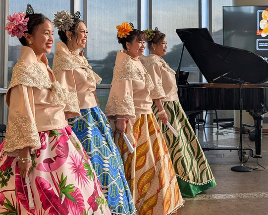 Women with beautifully patterned traditional Asian clothing with intricately embroidered tops and shawls stand together in a group of 4.