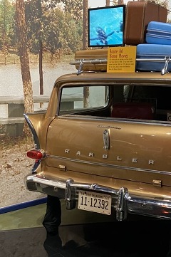 The rear portion of a Travelodge, with a full luggage wrap atop the vehicle, and murals of Route 66 surrounding the installation.