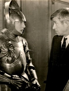 Humorist Will Rogers confronts a character dressed in a shining suit of armor on a movie set.