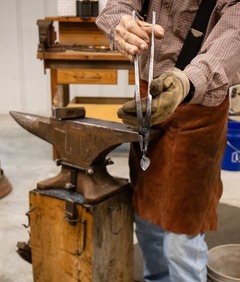 A blacksmith works on an anvil in a blacksmithing demonstration