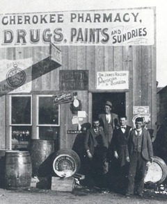 Cherokee Pharmacy Drugs, Paints, and Sundries historic image with 13 men standing in front of the Territorial business.