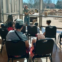 A History Center educator reads a book aloud to a large group of parents and children