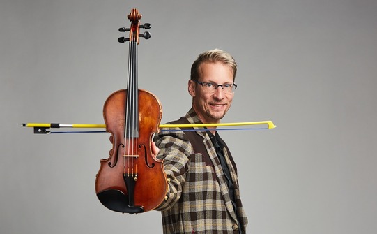 Musician Kyle Dillingham holds his fiddle and bow