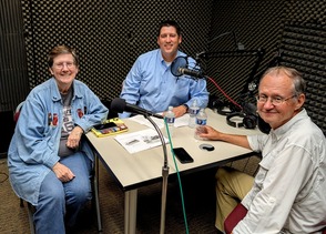 Trait Thompson, Dr. Bob Blackburn, and Kathy Anderson sit around a table with microphones in a sound-proof room.