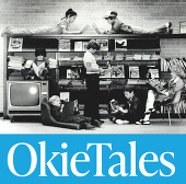 Children in chairs, on bookshelves, standing and all holding books,  reading.