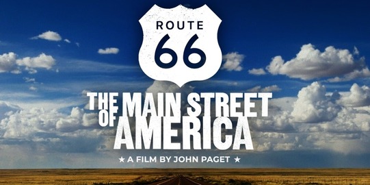 Cumulus clouds rise above a symmetrical view of a wheat field with the Route 66 highway dividing the lower center of the image.