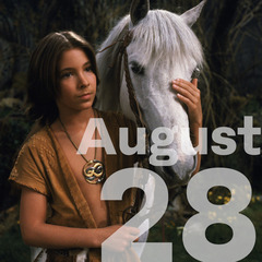 A young boy in rustic clothing holds the head of a white horse that is standing beside him.