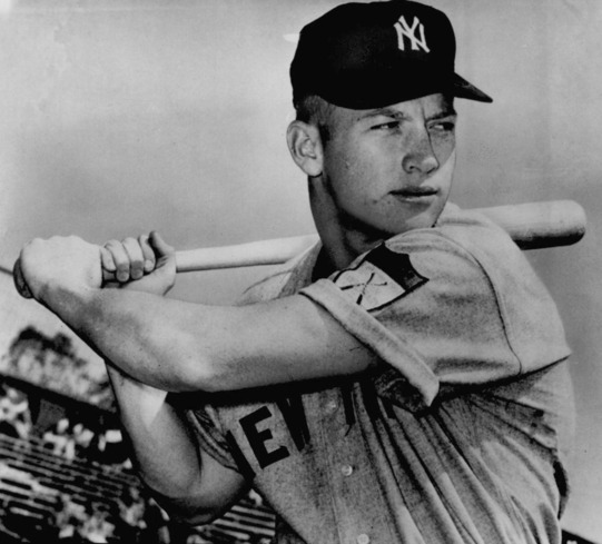 Mickey Mantle wearing a New York Yankees uniform with a bat resting on his right shoulder.