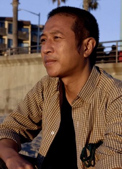 Filmmaker Tony Nguyen looks to the seascape, taking a moment to kneel in the sand of the beach