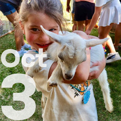 A young girl with her family holds a baby goat at the Family Farm Day activities.
