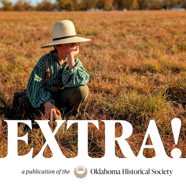 A young boy crouches in a field with oversized historical clothing and a hat low on his head. He is watching the distance with a hand under his chin.