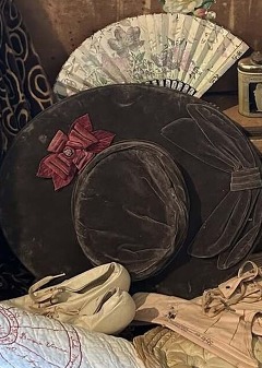 A Trunk of women's clothing from the 1800s, including hats, dresses, quilts, corsets, and hanging clothes.