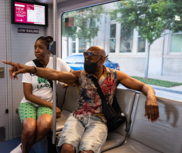 Masked man riding OKC streetcar pointing out the window.