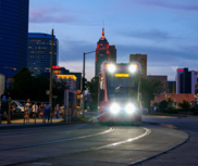 Streetcar driving at night with bright lights on tracks.