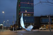 Large feather sculpture lit up at nighttime at Scissortail Park in front of the Omni hotel