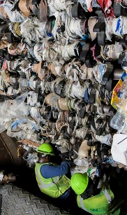 Workers at a recycling sorting facility climb into industrial equipment to cut out plastic bags that have been caught in cogs.