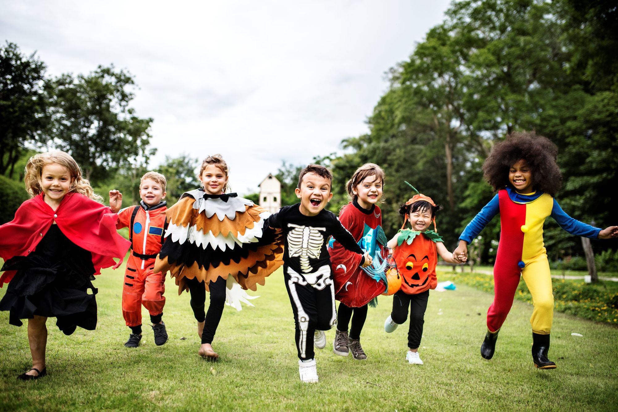 Little kids in costumes run around outside during a Halloween party
