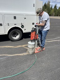 ODAV Staff member standing over a core drill with a white truck in the background