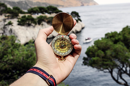 Compass opened in a man's hand overlooking coastline