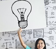 Girl sitting on the floor holding a posterboard with a lightbulb drawn on it