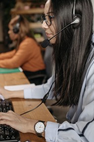 Woman providing helpdesk support at computer with headset