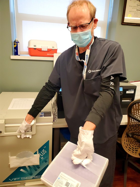 doctor in white coat with mask gloves and vaccine box
