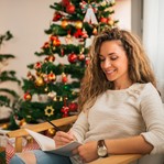 positive-woman-journaling-near-Christmas-tree