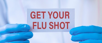 photo of hands holding a little sign saying "get your flu shot"