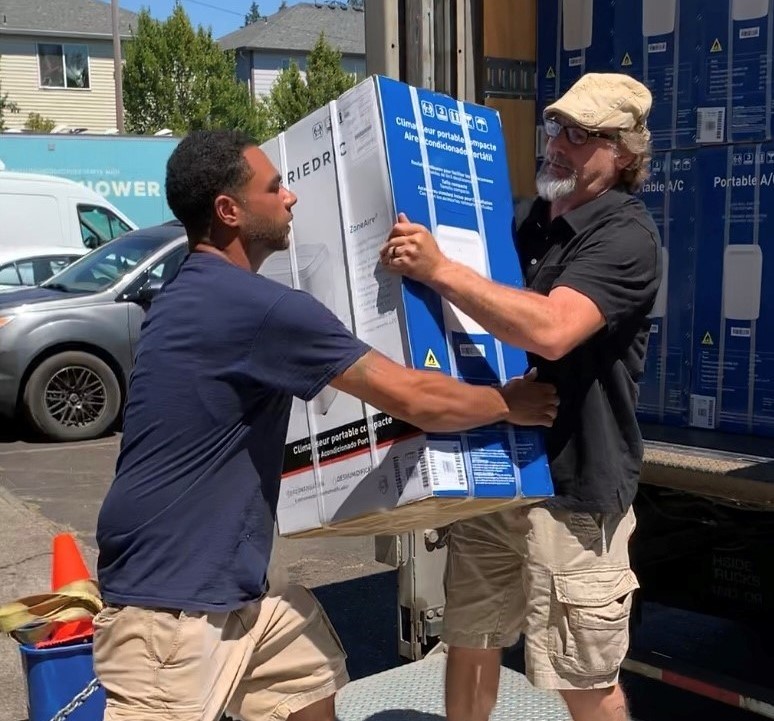 Image shows two people carrying a portable AC unit