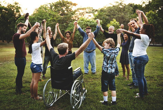 group of diverse people standing in a circle holding and raising hands