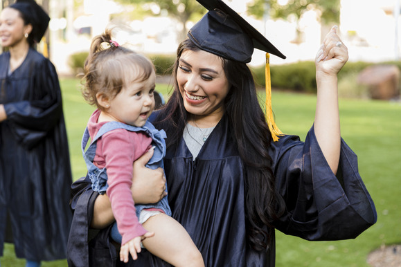 woman in graduation cap and gown holding a small child