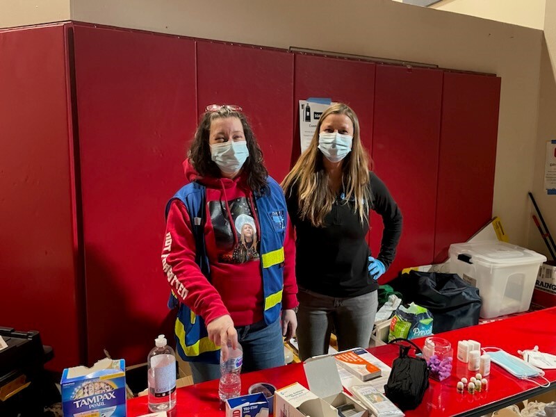 ODHS staff wear masks and stand at a supply table in a warming center