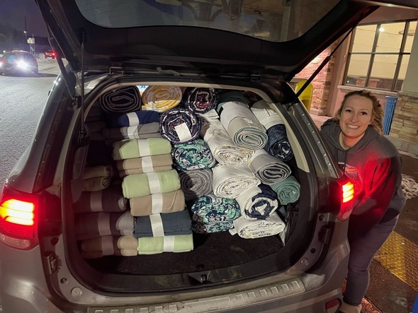 Megan Lindsey smiles next to a trunk full of blankets to be donated to a warming shelter during the January ice storms