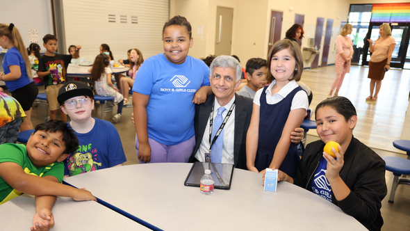 ODHS Fariborz Pakseresht sits at a school lunch table with a group of kids