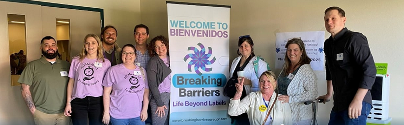a group of people standing next to a banner welcoming people to Breaking Barriers