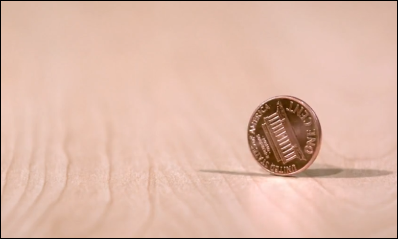 A single penny on a wooden table. 