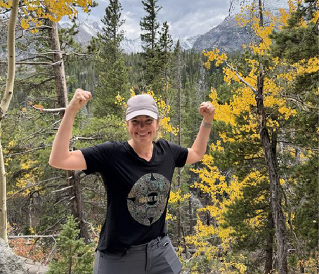 smiling woman flexing arms on mountain path