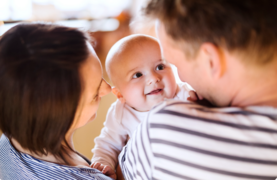 smiling baby with two adults
