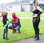 Spiderman and Bat Woman greet a child in foster care outdoors