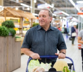 smiling man with shopping cart in grocery store